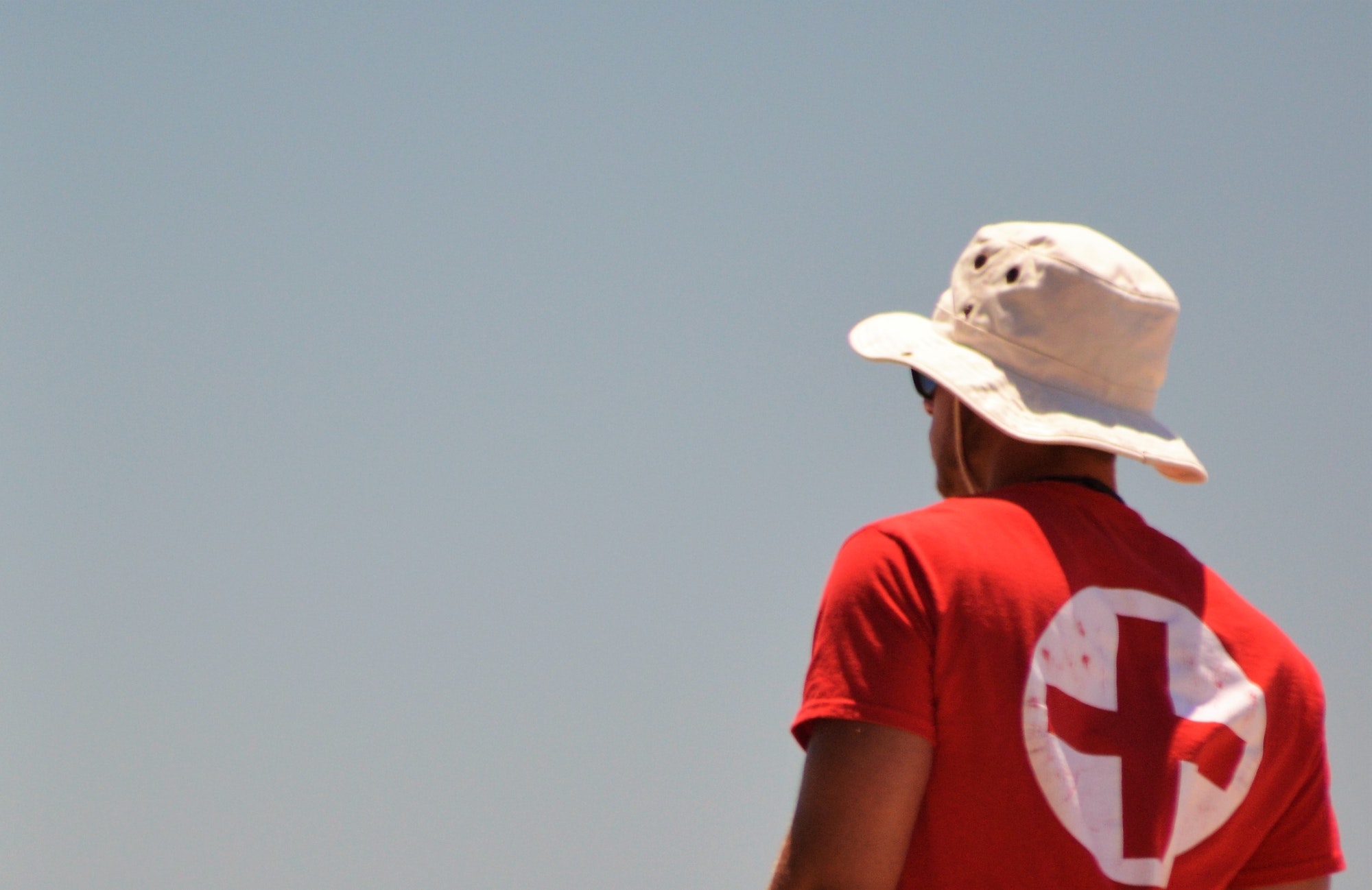 A lifeguard with a cross on his back patrolling the beach front. Safety first. Jobs that save lives